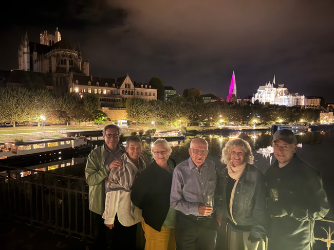 Passengers on the Passerelle in Auxerre at night, with the illuminated cathedral and abbey beyond